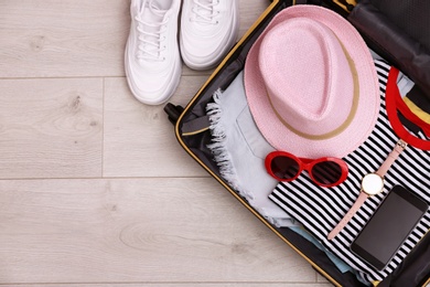 Photo of Packed suitcase on wooden background, top view. Space for text