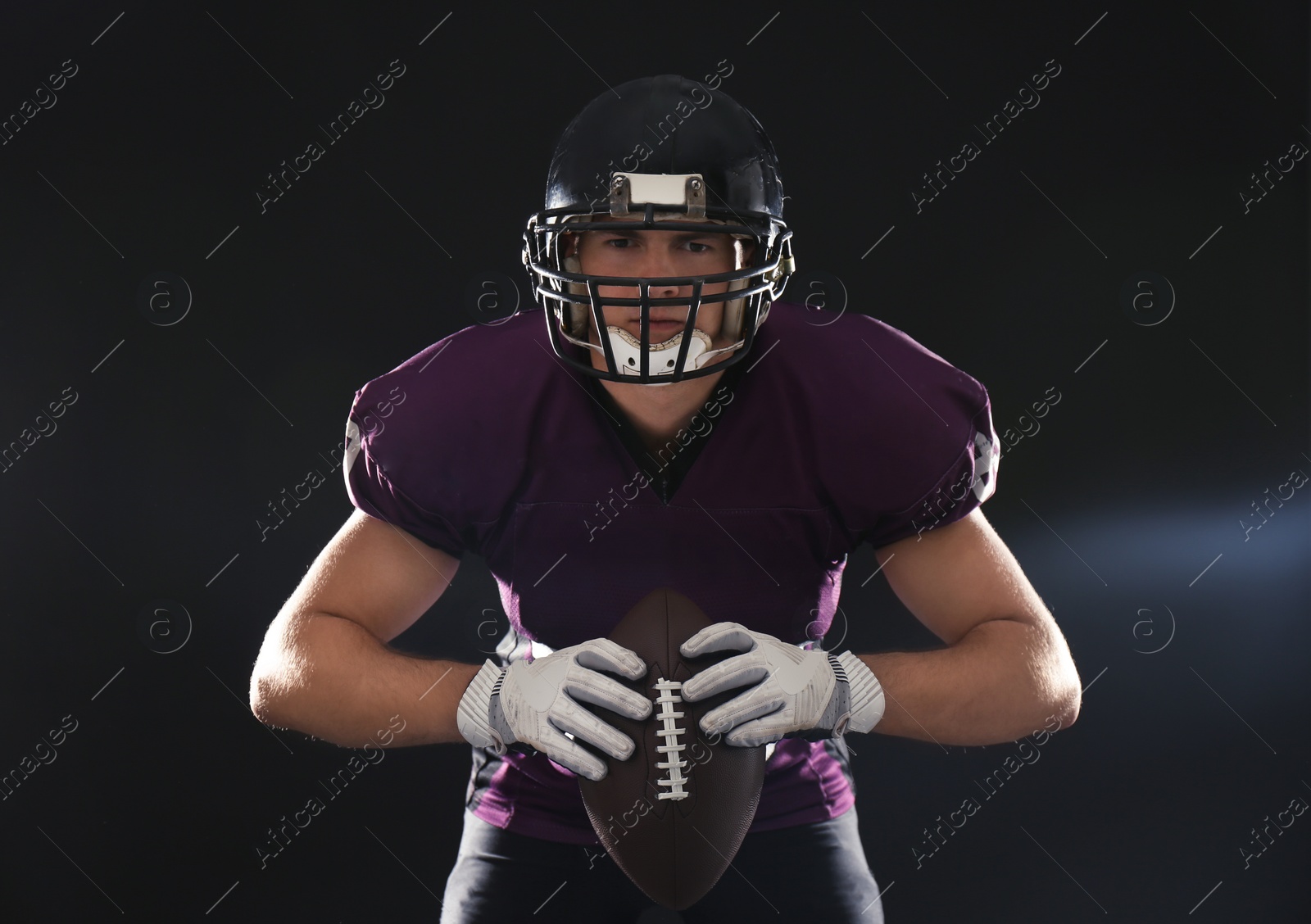 Photo of American football player with ball on dark background