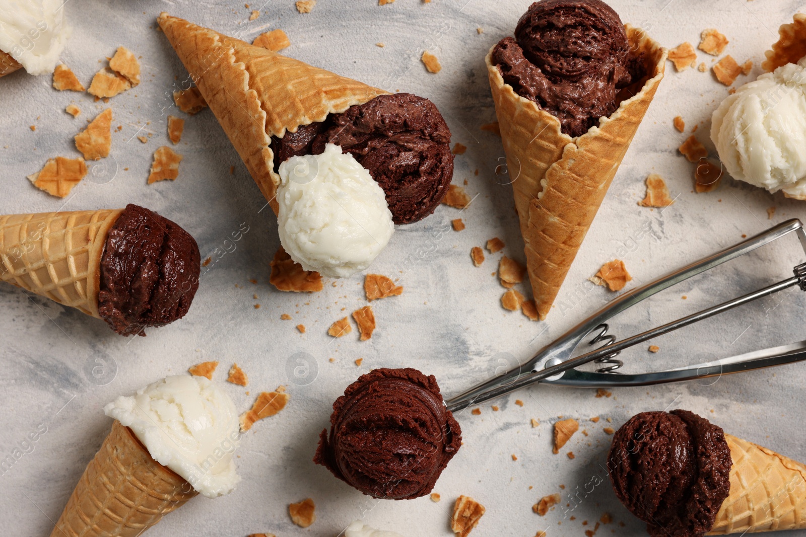 Photo of Composition with tasty ice cream scoops in waffle cones on light textured table, above view