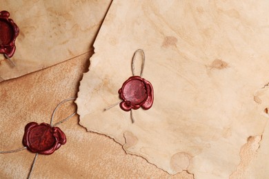 Photo of Sheets of old parchment paper with wax stamps as background, top view