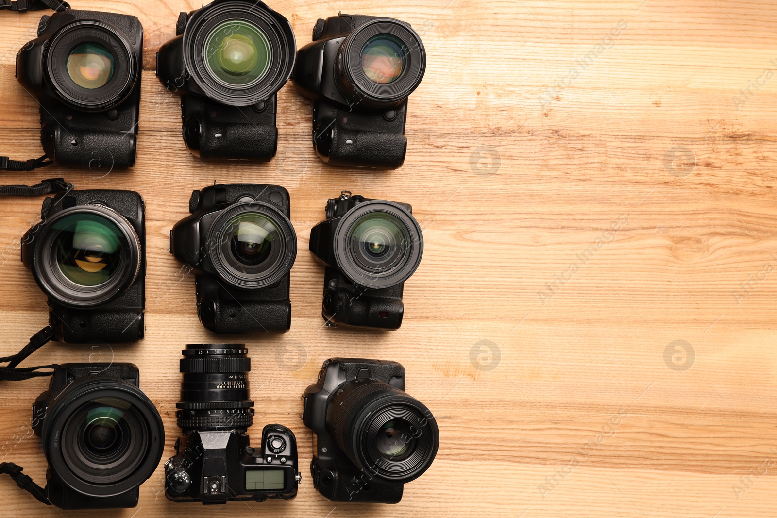 Photo of Modern different cameras on wooden table, flat lay. Space for text