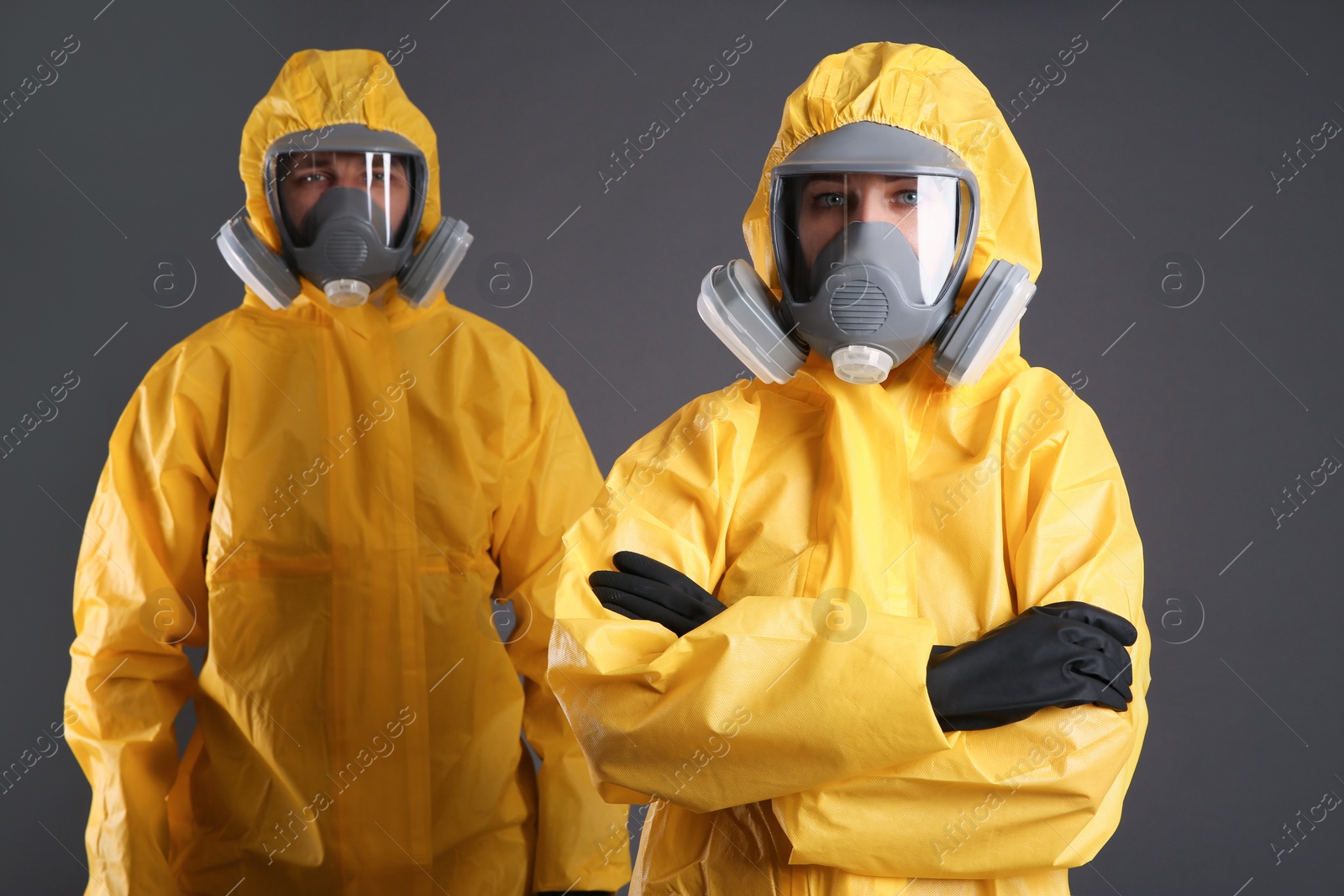 Photo of Man and woman wearing chemical protective suits on grey background. Virus research