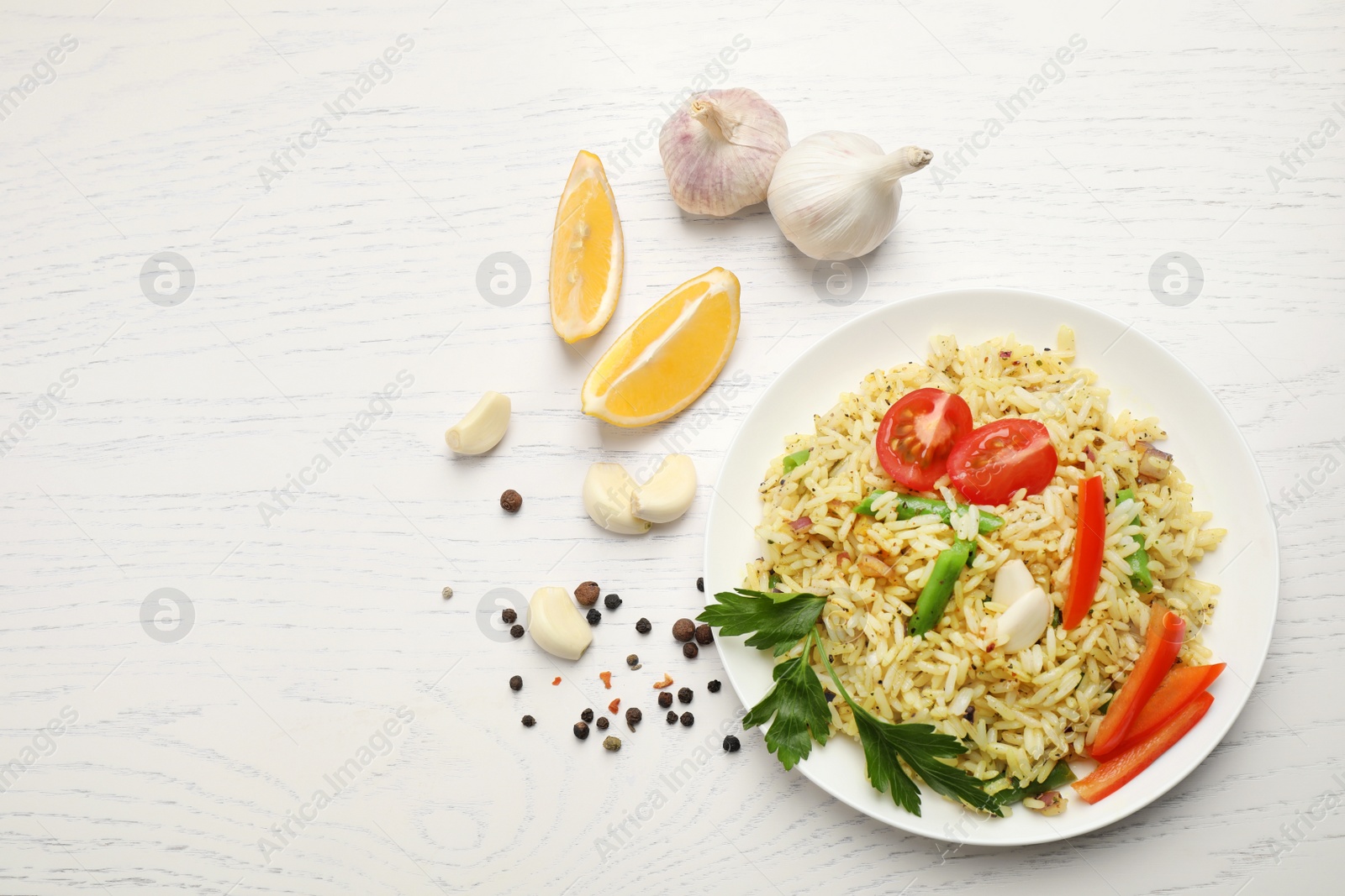 Photo of Tasty rice pilaf with vegetables on white wooden table, flat lay