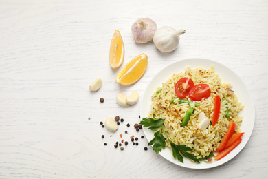 Photo of Tasty rice pilaf with vegetables on white wooden table, flat lay