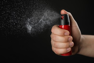Image of Man using pepper spray on black background, closeup
