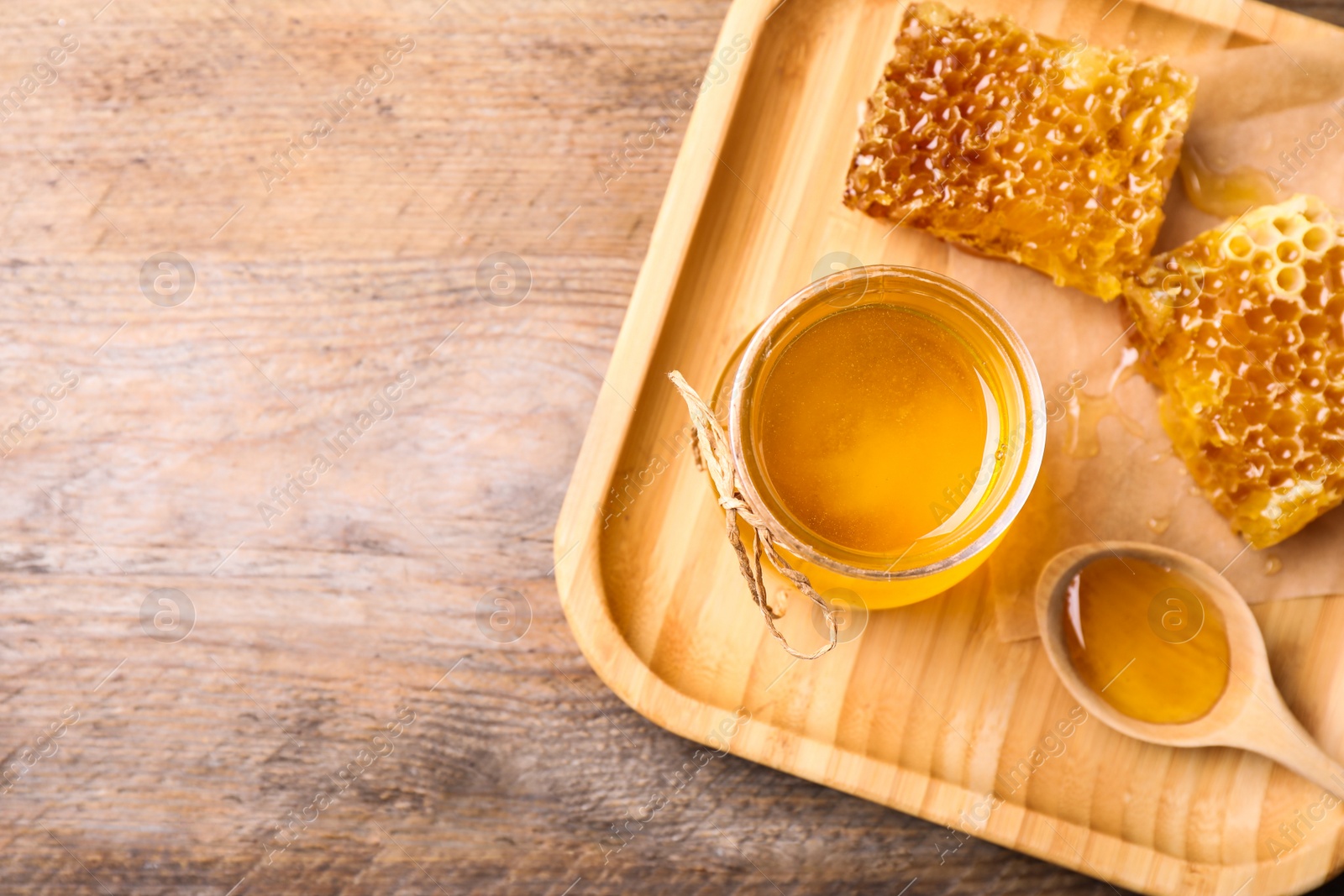 Photo of Tasty aromatic honey on wooden table, flat lay. Space for text