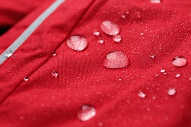 Photo of Red waterproof fabric with water drops as background, closeup