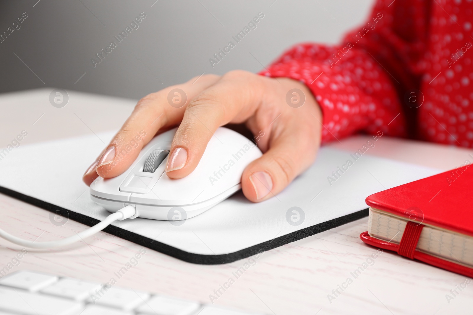 Photo of Woman using modern wired optical mouse at office table, closeup