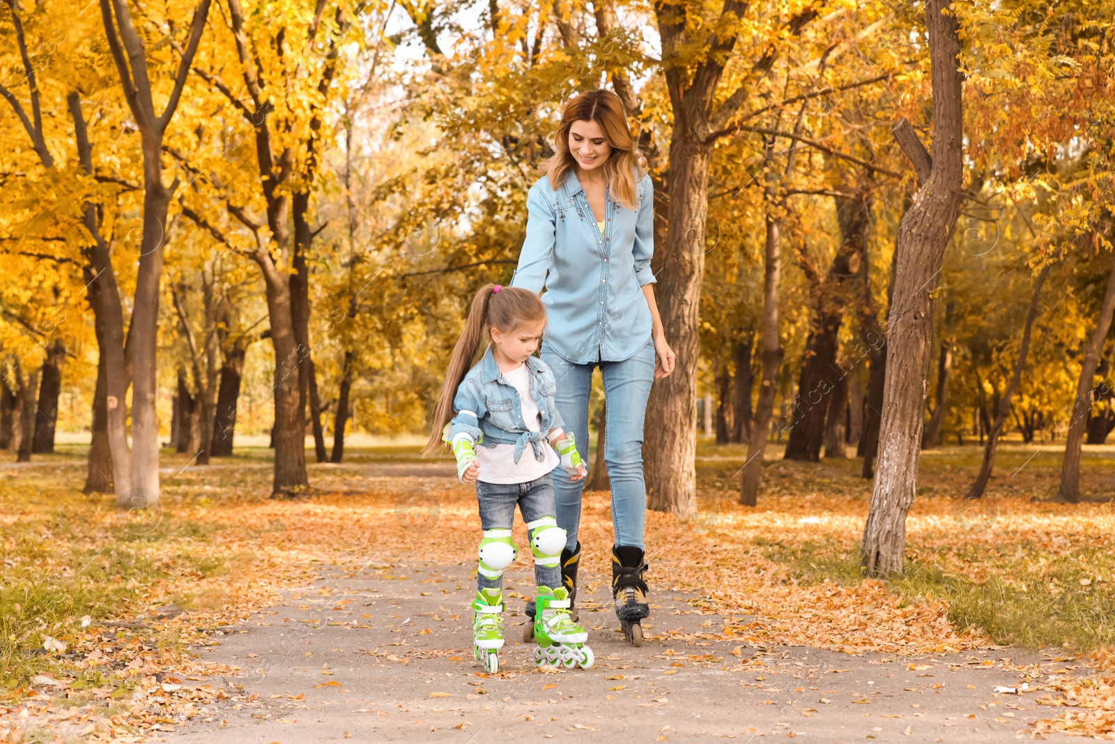 Photo of Mother and her daughter roller skating in autumn park