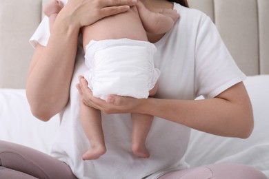 Photo of Mom holding her baby in diaper at home, closeup