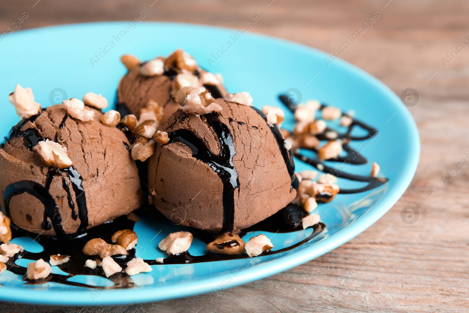 Photo of Plate of chocolate ice cream with nuts on wooden table, closeup. Space for text