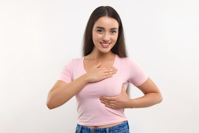Beautiful young woman doing breast self-examination on white background