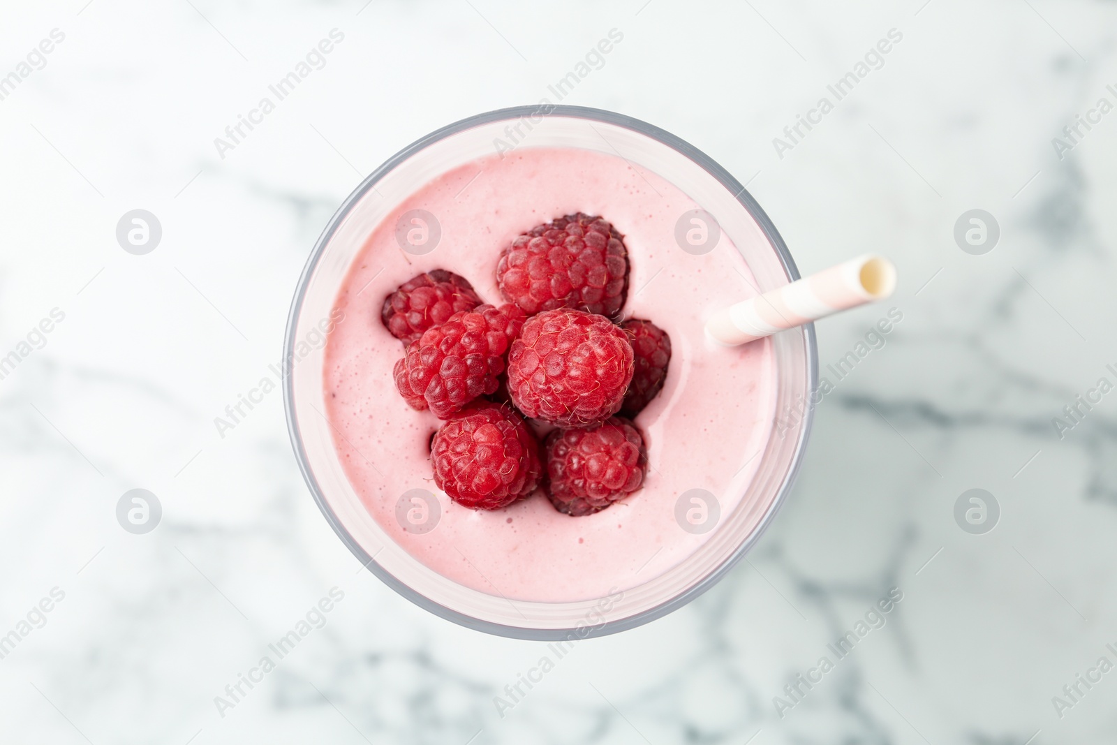 Image of Yummy raspberry smoothie in glass on white marble table, top view