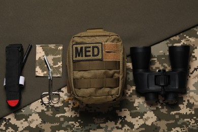 Military first aid kit and binoculars on color background, flat lay.