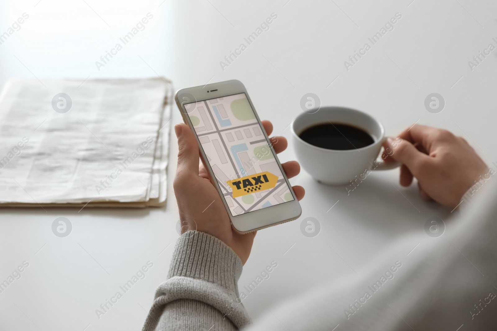 Photo of Man ordering taxi with smartphone at white table, closeup