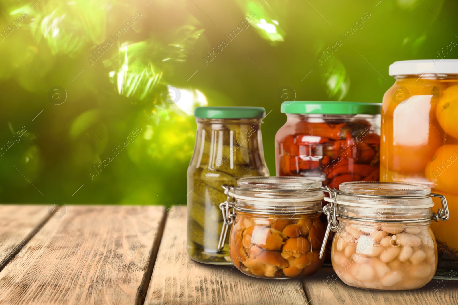 Image of Jars of different pickled foods on wooden table against blurred background, space for text