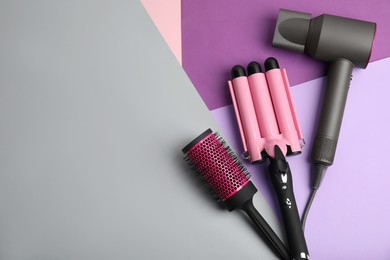 Photo of Hair dryer, brush and triple curling iron on color background, flat lay. Space for text