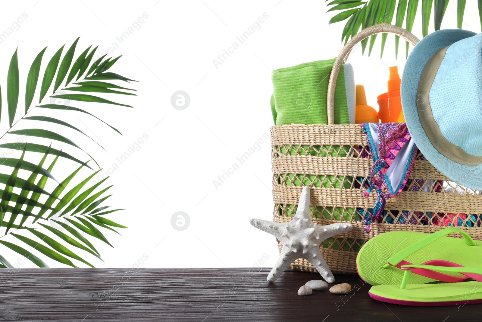 Photo of Bag with different beach objects on wooden table against white background. Space for text