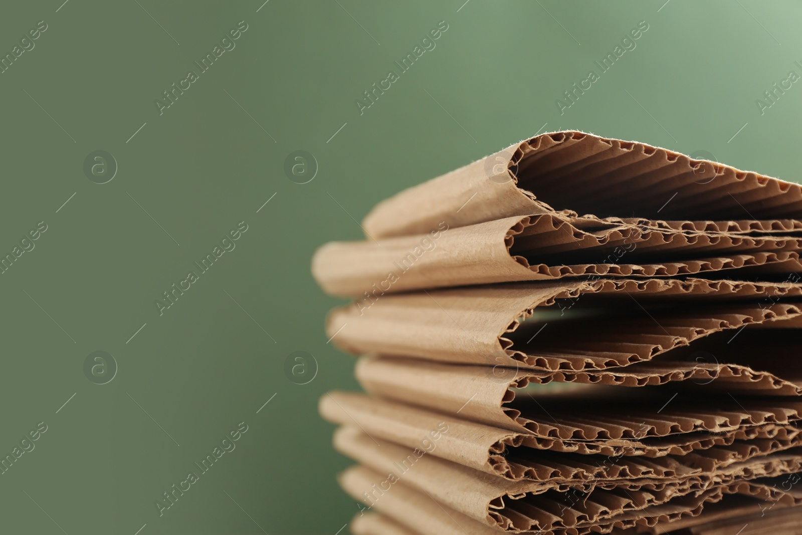 Photo of Stack of cardboard on green background, closeup with space for text. Recycling concept