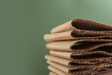Photo of Stack of cardboard on green background, closeup with space for text. Recycling concept
