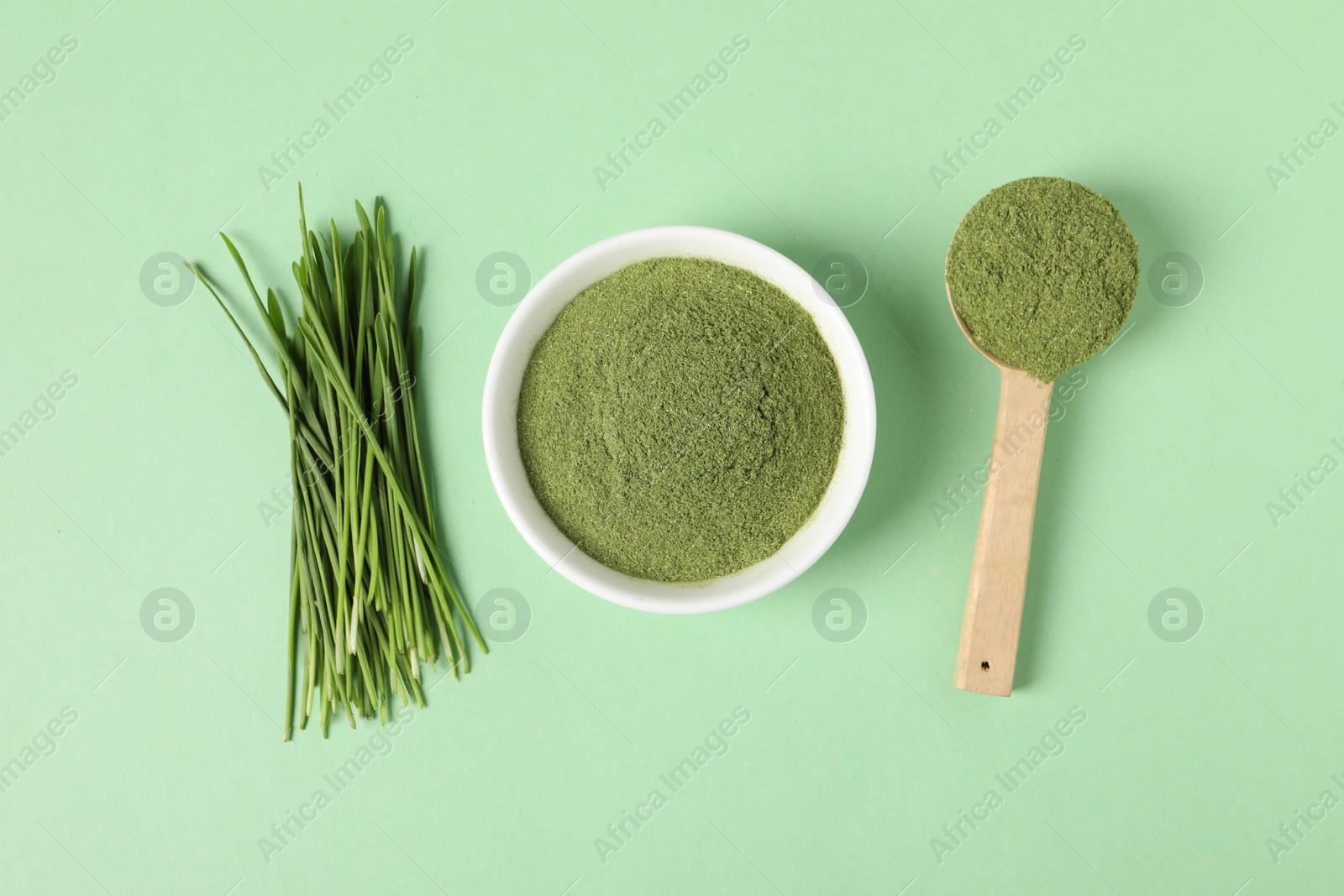 Photo of Wheat grass powder and fresh sprouts on green table, flat lay