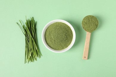 Wheat grass powder and fresh sprouts on green table, flat lay