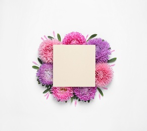 Composition with beautiful aster flowers and blank card on white background, top view. Space for text