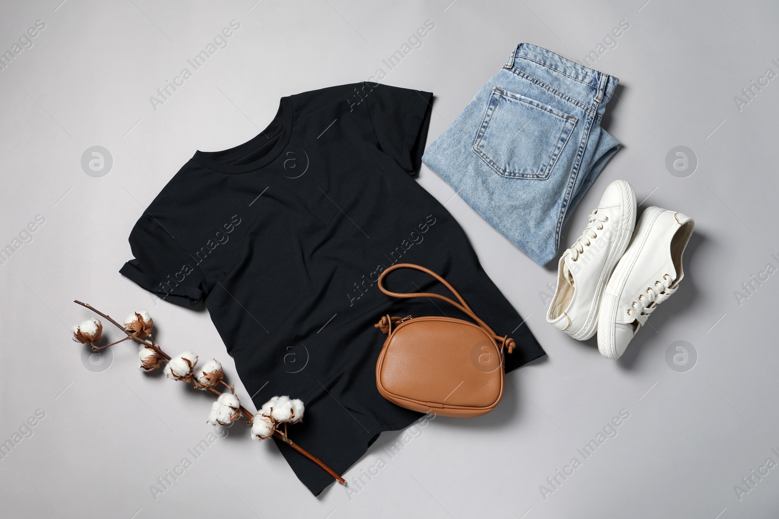 Photo of Stylish t-shirt, jeans and sneakers on light grey background, flat lay