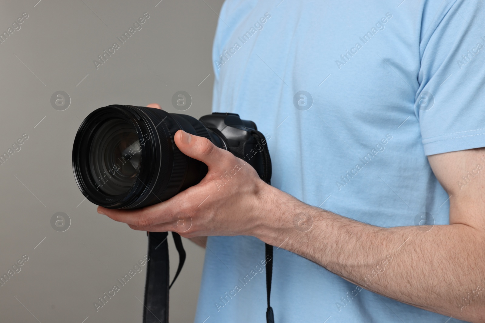 Photo of Photographer holding camera on grey background, closeup