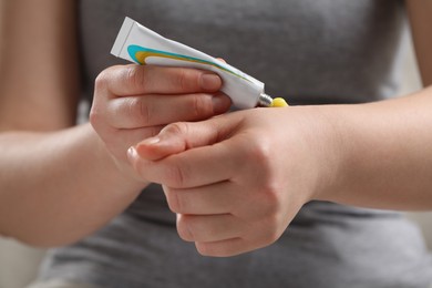 Photo of Woman applying ointment from tube onto her hand, closeup
