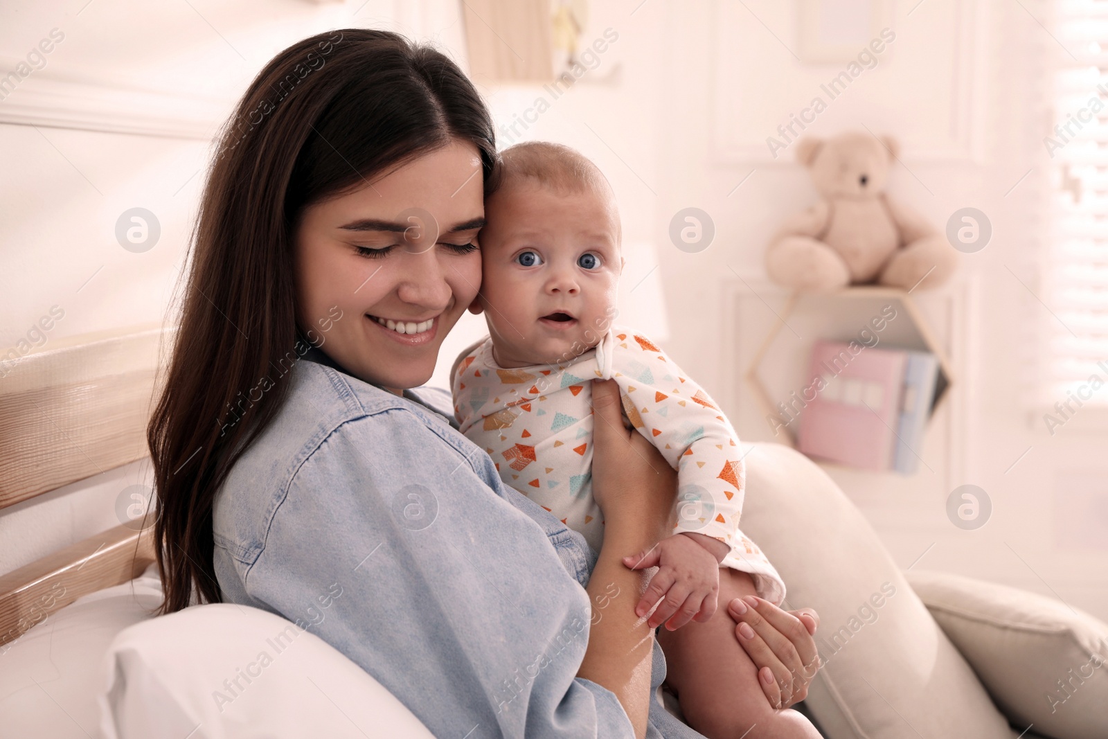 Photo of Mother with her cute baby on bed at home