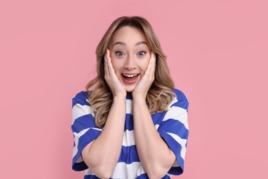 Portrait of happy surprised woman on pink background