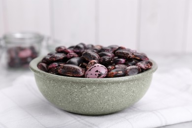 Photo of Bowl with dry kidney beans on table, closeup