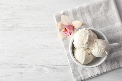 Photo of Cup with tasty vanilla ice cream on wooden background, top view