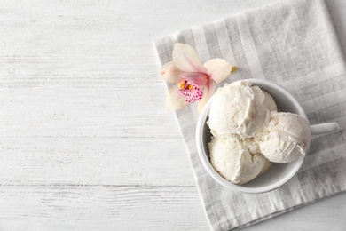 Cup with tasty vanilla ice cream on wooden background, top view