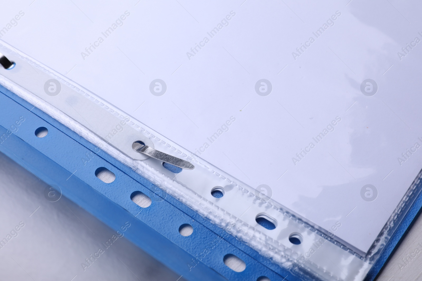 Photo of File folder with punched pockets and paper sheets on white background, closeup