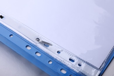 File folder with punched pockets and paper sheets on white background, closeup