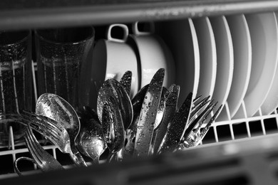 Photo of Set of clean wet tableware in dishwasher, closeup