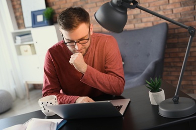 Young man using laptop at table indoors