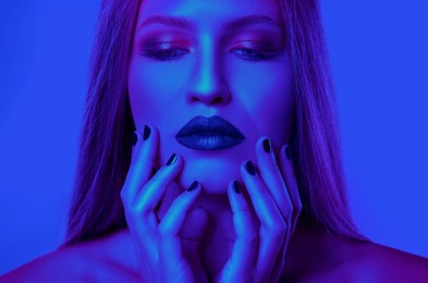 Young woman with beautiful makeup posing in neon lights