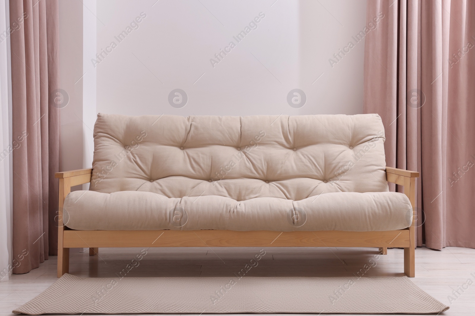 Photo of Comfortable sofa with rug in cozy light room. Interior design