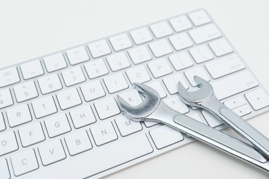 Photo of Wrenches and computer keyboard on light background. Concept of technical support