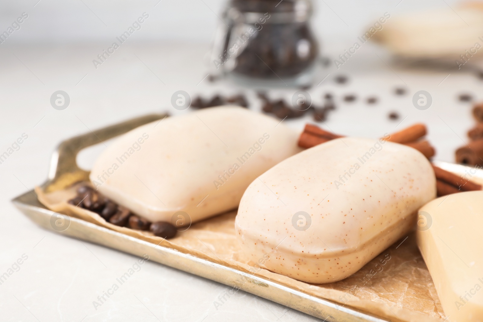 Photo of Different soap bars in tray with parchment paper on light table, closeup