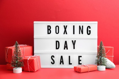 Photo of Lightbox with phrase BOXING DAY SALE and Christmas decorations on red background
