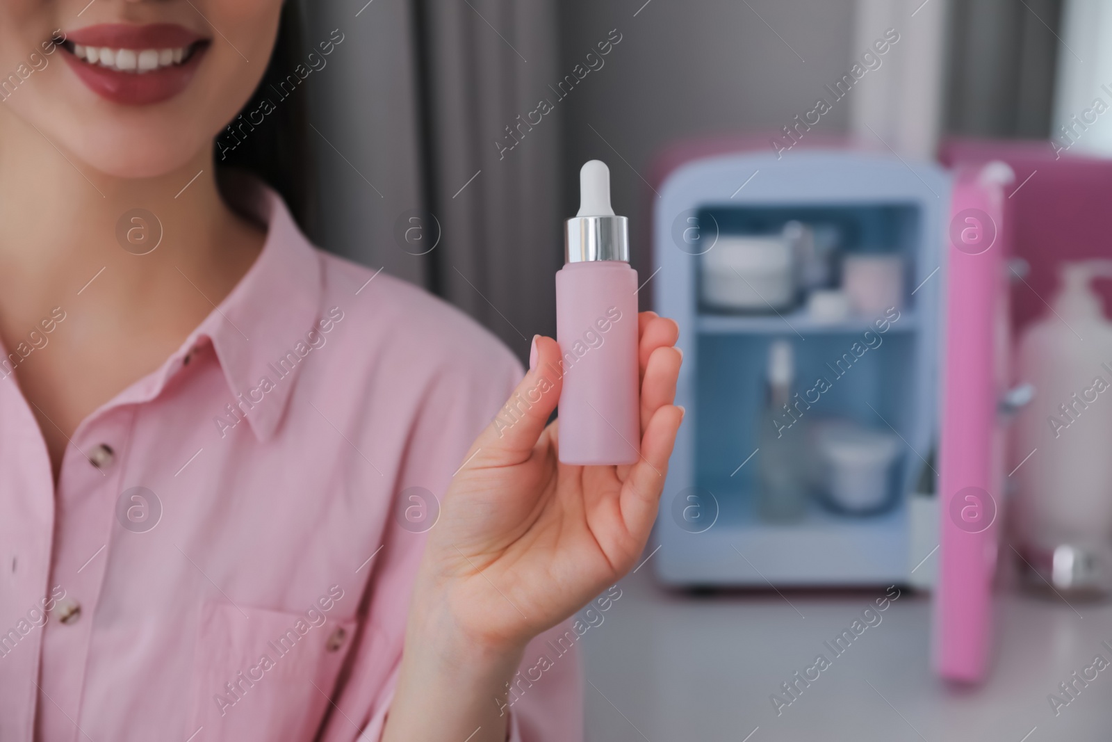Photo of Woman with cosmetic product out of mini refrigerator indoors, closeup