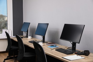 Open office interior. Modern workplaces with computers near light grey wall