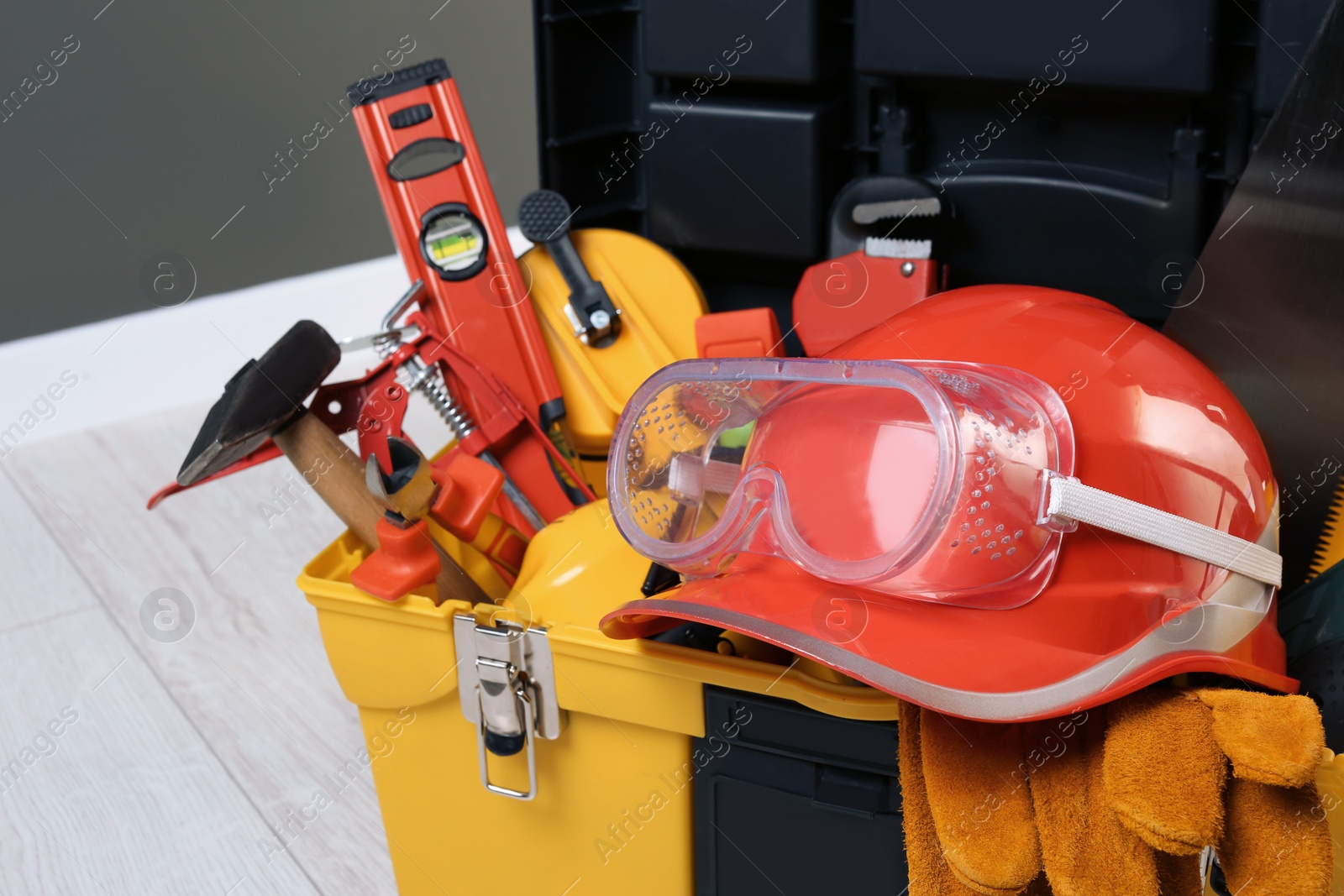 Photo of Box with professional tools for repair on white wooden floor, closeup