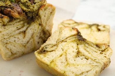 Photo of Freshly baked pesto bread on white table, closeup