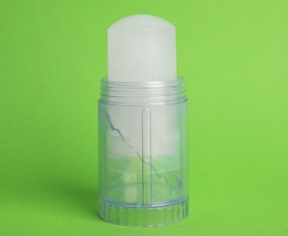 Photo of Natural crystal alum stick deodorant on green background