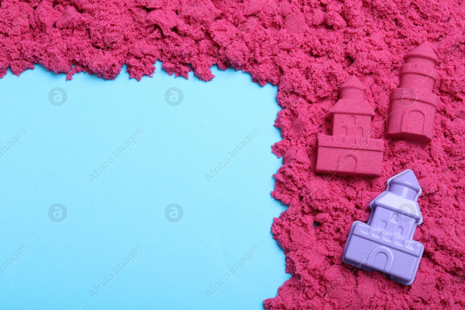 Photo of Pink kinetic sand and toy on light blue background, flat lay. Space for text